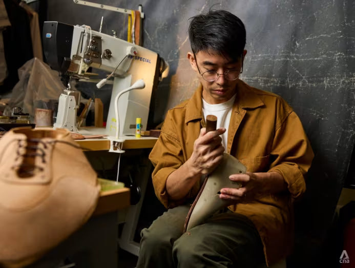 Tor Cheng Yao working on a shoe in a workshop with sewing machine in the background